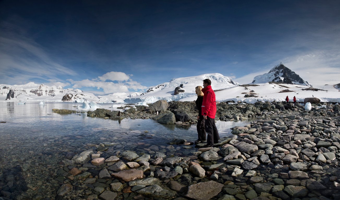 Panoramic view of Antarctic expedition with travelers landing on pristine snow-covered shore